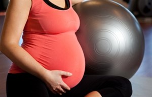 Pregnancy women in activewear sitting next to a swiss ball.